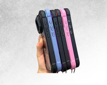 May include: A hand holds a stack of phone cases in various colors: black, light blue, purple, orange, and pink. Each case has a black frame and a clear back. The cases are designed to fit a phone with a camera lens attachment.