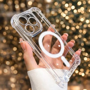 以下が含まれることがあります： 白の円形と長方形のデザインが施された透明な携帯電話ケース。ケースは透明で、カメラを保護するための隆起したエッジが付いています。このケースはスマートフォンに合うように設計されています。