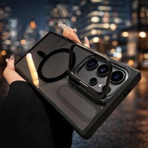 Peut inclure: Coque de téléphone noire avec un support de bague intégré et un cercle magnétique au dos. Le boîtier a une finition claire et brillante et un cadre noir. Le support de bague est également noir et porte l'inscription "FUUCASE".