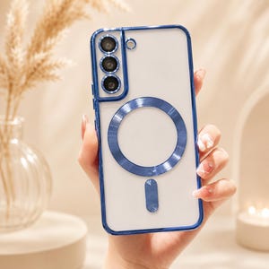 May include: Clear phone case with a blue frame and accents. The case features a circular design and a rectangular accent on the back. The phone case has a clear back and is held in a hand.