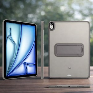 Op de afbeelding: Een grijze iPad-hoes met een doorzichtige achterkant en een ingebouwde standaard. De hoes heeft een grijs frame en een uitsparing voor de camera. Het scherm toont een blauw en wit abstract ontwerp. Het woord "Pad" staat op de achterkant.