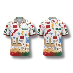 May include: White button-up shirt with a Moroccan theme, featuring the country's flag, landmarks, and the year 2026. The shirt has a colorful design with red, green, and gold accents, and the number 0 and 10 on the sleeves.