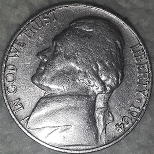 May include: A close-up of a silver 1964 nickel. The coin features a profile of Thomas Jefferson, with the words "IN GOD WE TRUST" and "LIBERTY" visible. The year "1964" is also displayed.