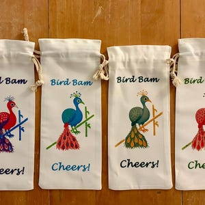 May include: Six white wine bottle bags with drawstring closures. Each bag features a colourful peacock illustration with the text "Bird Bam" and "Cheers!". The peacock designs vary in colour, including blue, red, and green.
