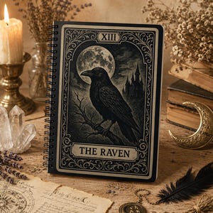 Könnte beinhalten: Ein spiralgebundenes Notizbuch mit einer schwarz-weißen Tarot-Illustration, die einen Raben auf einem Ast unter einem Vollmond und einer Burgsilhouette zeigt. Das Cover trägt die römische Ziffer XIII und den Schriftzug THE RAVEN in einem Rahmen.