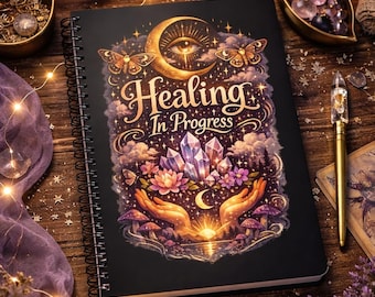 Könnte beinhalten: Ein schwarzes Spiralnotizbuch mit dem Schriftzug "Healing In Progress" und einem Himmelsdesign mit Mond, Schmetterlingen und Kristallen. Das Bild enthält Kerzen, Kristalle und einen goldenen Stift, was ein mystisches Thema erzeugt.