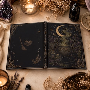 Peut inclure: Un livre relié ouvert avec une couverture noire ornée d'illustrations en feuille d'or. La page de gauche montre un balai et un petit livre, tandis que la page de droite représente un chaudron avec de la fumée, un croissant de lune et des fioles.