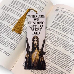 Puede incluir: Marcap&aacute;ginas con el texto "WHO ARE WE SENDING OFF TO MEET DAD" y una imagen de Jes&uacute;s sosteniendo dos rifles. El marcap&aacute;ginas tiene una borla dorada y est&aacute; en un libro abierto.