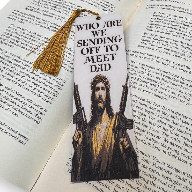 Puede incluir: Marcap&aacute;ginas con el texto "WHO ARE WE SENDING OFF TO MEET DAD" y una imagen de Jes&uacute;s sosteniendo dos rifles. El marcap&aacute;ginas tiene una borla dorada y est&aacute; sobre un libro abierto.