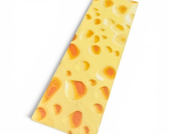 Puede incluir: Un objeto decorativo rectangular con temática de queso, amarillo con detalles naranjas y agujeros. El objeto es de un amarillo brillante con detalles naranjas, y los agujeros varían en tamaño y forma. Sobre un fondo blanco.