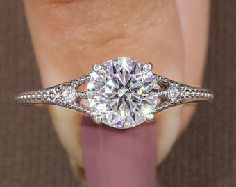 May include: A silver-coloured ring featuring a large, round, brilliant-cut clear centre stone held by four prongs. The band displays a textured, beaded metal finish with a small, round, clear accent stone embedded on each side of the centre setting.