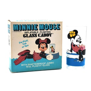 May include: A box with a Minnie Mouse illustration and the text "Minnie Mouse Inflatable-Floating Glass Caddy" and "For Pool, Tub or Spa" and "With Shatterproof Jumbo 19 oz. Plastic Glass". The box is next to a clear glass with a Minnie Mouse illustration on it.