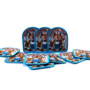 May include: A stack of blue and white embroidered patches featuring a cartoon fox wearing a nurse's uniform and the text "Hospital Tour".