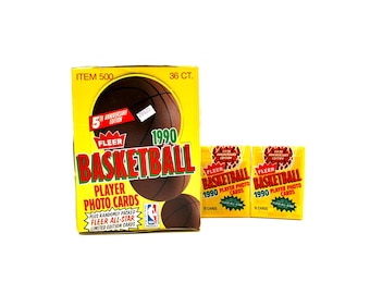 May include: A yellow box of 1990 Fleer Basketball Player Photo Cards with a basketball graphic. The box reads "5th Anniversary Edition" and "36 CT." Two smaller packs of cards are also visible.