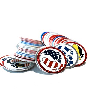 May include: A stack of colorful round stickers with footprints and flags. The stickers are red, white, blue, yellow, and black. The flags include the American flag, the Malaysian flag, the Finnish flag, and the flag of the Bahamas.