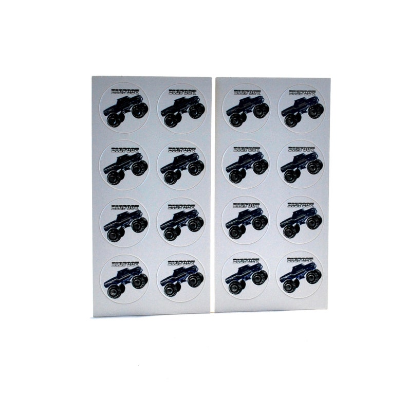 May include: Two sheets of stickers featuring a black monster truck design. Each sticker is round with the truck in the center and text at the top. The stickers are on a white background.