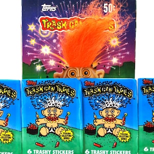 Pu&ograve; includere: Una collezione di figurine Topps Trash Can Trolls vintage. L'immagine presenta una scatola con un design di troll e il testo "Trash Can Trolls". Sotto, quattro pacchetti di adesivi con lo stesso tema. Ogni pacchetto contiene 6 adesivi trash.