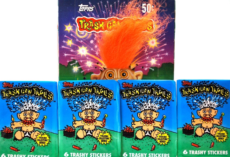 Pu&ograve; includere: Una collezione di figurine Topps Trash Can Trolls vintage. L'immagine presenta una scatola con un design di troll e il testo "Trash Can Trolls". Sotto, quattro pacchetti di adesivi con lo stesso tema. Ogni pacchetto contiene 6 adesivi trash.