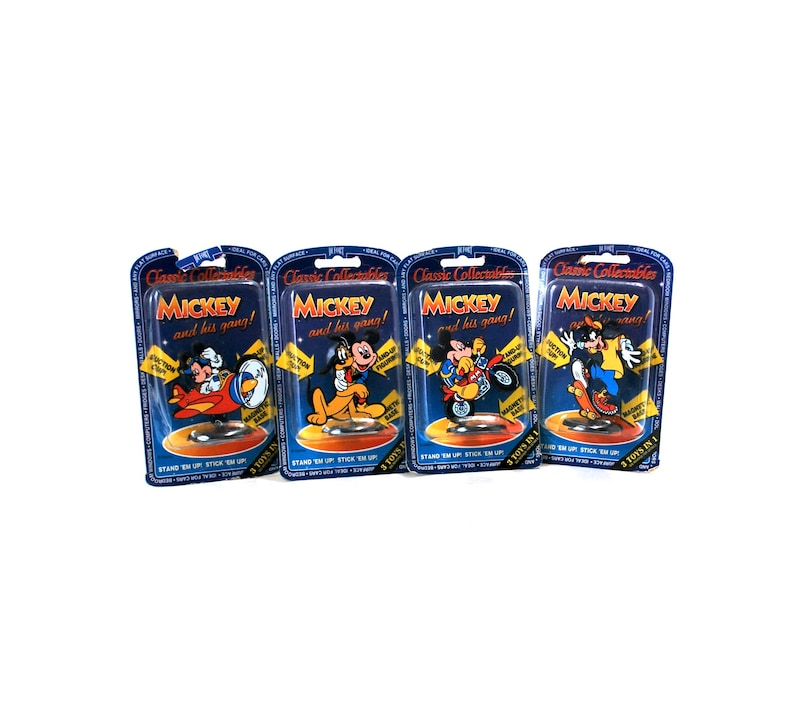 Puede incluir: Tres paquetes de cart&oacute;n azul y amarillo con Mickey Mouse y su pandilla! impresos en la parte delantera. Cada paquete presenta un personaje diferente de Mickey Mouse y dice "3 juguetes en 1" en la esquina inferior derecha.