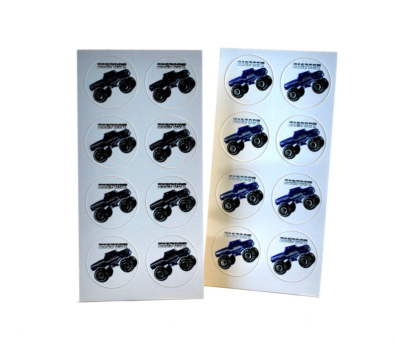May include: Two sheets of round stickers featuring monster trucks. One sheet has black trucks, the other has blue trucks. Each sticker has the word "BIGFOOT" above the truck image.