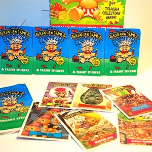 Pu&ograve; includere: Una collezione di figurine e pacchetti di adesivi vintage "Trash Can Trolls". I pacchetti sono blu con un'illustrazione di un troll dei cartoni animati e la scritta "6 Trashy Stickers". Le singole carte presentano vari personaggi e scene di troll.