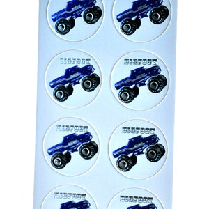 May include: Sheet of round stickers featuring a blue monster truck design with the word "BIGFOOT" in a silver font. The truck has large black tires and is set against a white background. The stickers are likely for crafts or party favors.