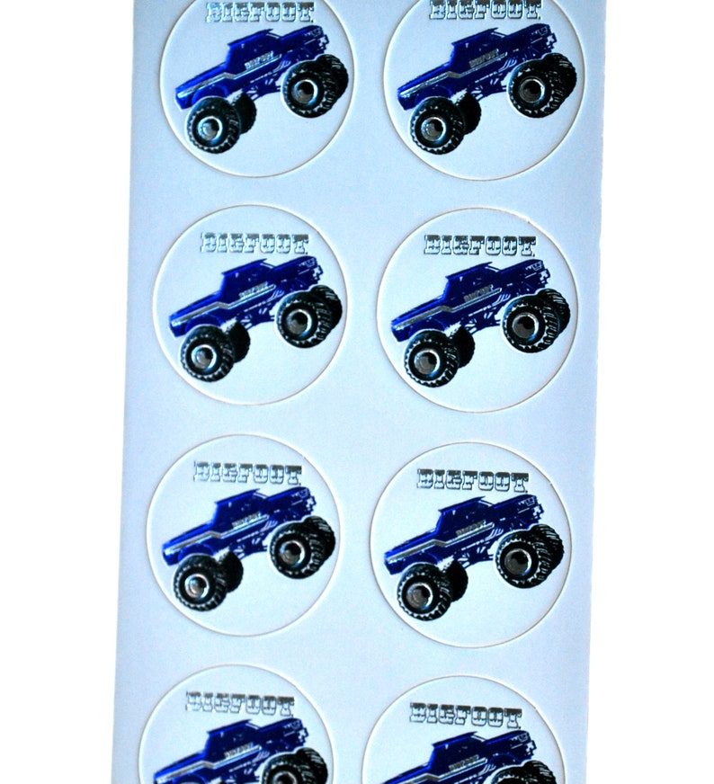 May include: Sheet of round stickers featuring a blue monster truck design with the word "BIGFOOT" in a silver font. The truck has large black tires and is set against a white background. The stickers are likely for crafts or party favors.