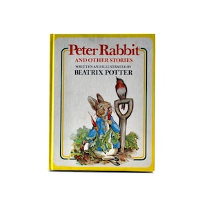 May include: A yellow book with a picture of Peter Rabbit on the cover. The title is "Peter Rabbit and Other Stories" written and illustrated by Beatrix Potter.