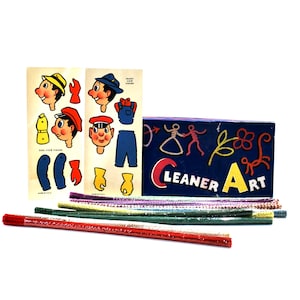 May include: A blue box with the words "Cleaner Art" printed on it. The box contains colorful pipe cleaners and two sheets of paper with a cartoon character on them. The character is wearing a blue shirt and overalls.