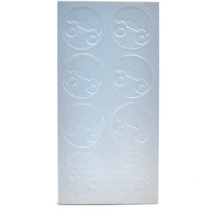 May include: A sheet of eight silver-colored stickers. Each sticker is a circle with a raised, embossed design of a small car. The stickers are arranged in two columns of four.