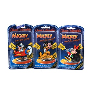 Puede incluir: Tres paquetes sin abrir de juguetes Classic Collectables Mickey y su pandilla. Cada paquete presenta un personaje diferente de Mickey Mouse sobre un fondo azul con el texto "Classic Collectables Mickey y su pandilla!" en blanco.