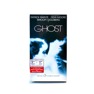May include: A VHS tape cover for the movie "Ghost" starring Patrick Swayze, Demi Moore, and Whoopi Goldberg. The cover features a close-up of a couple embracing, with the title of the movie in large, white letters.