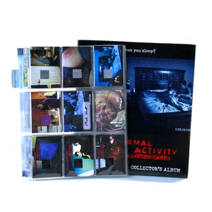 May include: A collector's album and trading cards from the movie "Paranormal Activity." The album is black with the movie title in red and white. The cards are in plastic sleeves, featuring scenes from the film. The album reads "Collector's Album."