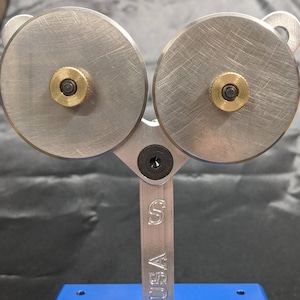 May include: A silver metal reloading tool with two wheels and a blue base. The tool is labeled "USA" on the side.