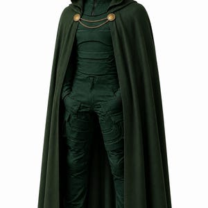 May include: A dark green hooded cloak with gold-toned circular clasps and a chain connector, worn over a matching dark green long-sleeved top with a high zippered collar and dark green cargo-style trousers, paired with black leather boots.