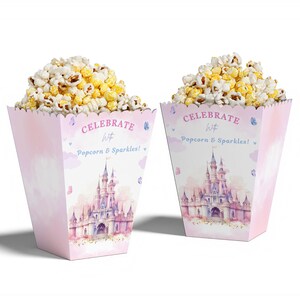 May include: Two pink popcorn boxes filled with popcorn. The boxes feature a castle design and the text "CELEBRATE With Popcorn & Sparkles!". The boxes are decorated with butterflies and clouds.