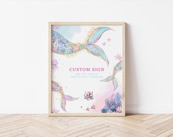 Può includere: Un cartello personalizzato incorniciato con un tema sirena. L'opera presenta illustrazioni ad acquerello di code di sirena, un polpo, coralli e il testo "CUSTOM SIGN". Il cartello è in una cornice di legno ed è esposto su un pavimento di legno.