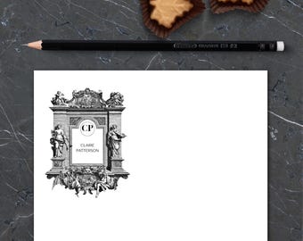 May include: A black and white stationery set featuring a decorative frame with the initials "CP" and the name "Claire Patterson". A black pencil and two leaf-shaped pastries are also visible.