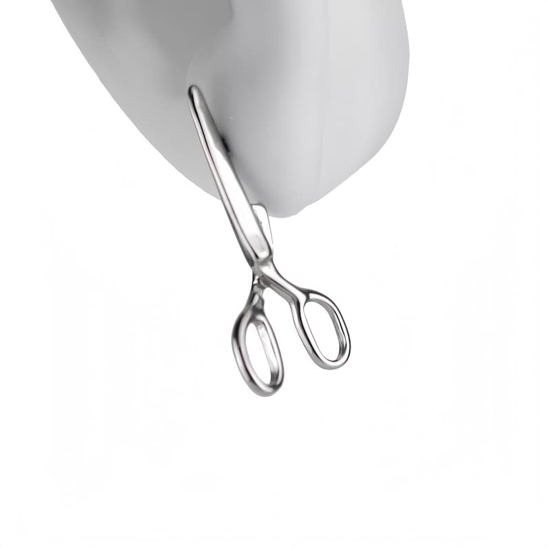 May include: A small, silver-colored metal earring shaped like a pair of scissors. The earring features two oval finger loops and two pointed blades, with a polished, reflective finish. It is designed to be worn in an earlobe piercing.