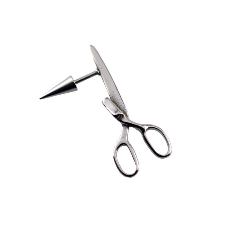 May include: A silver-toned metal body jewelry piece shaped like a pair of scissors with a pointed cone-shaped attachment extending from the side. The design features two oval finger loops and a long blade, crafted from a smooth, reflective material.