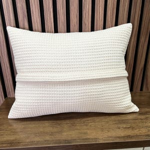 A close-up photograph of the back of the handcrafted waffle weave pillow, highlighting the precise sewing and the neatly integrated hidden zipper details that showcase artisanal care.
Eine Nahaufnahme der Rückseite des handgefertigten Waffelpikee-Kissens, die die präzise Verarbeitung und den sauber integrierten, verdeckten Reißverschluss zeigt und die handwerkliche Sorgfalt unterstreicht.