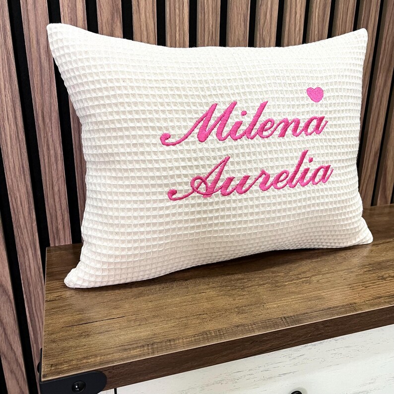 Handcrafted white waffle weave cushion with custom name embroidery, ideal personalized gift for baby girls and nursery room decor.

Handgemachtes Waffelkissen in Weiß mit Namensstickerei, ideales personalisiertes Geschenk für Mädchen und Dekoration fürs Babyzimmer.

Coussin artisanal gaufré blanc avec prénom brodé, cadeau personnalisé idéal pour petite fille et décoration de chambre d'enfant.