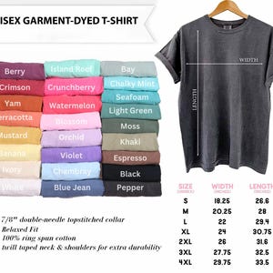 K&ouml;nnte beinhalten: Ein dunkelgraues Unisex-T-Shirt, gef&auml;rbtes Kleidungsst&uuml;ck, das auf einem Kleiderb&uuml;gel pr&auml;sentiert wird. Das Bild zeigt eine Farbkarte mit verschiedenen Hemdfarben, darunter Berry, Crimson und Island Reef. Gr&ouml;&szlig;en- und Ma&szlig;angaben sind ebenfalls enthalten.
