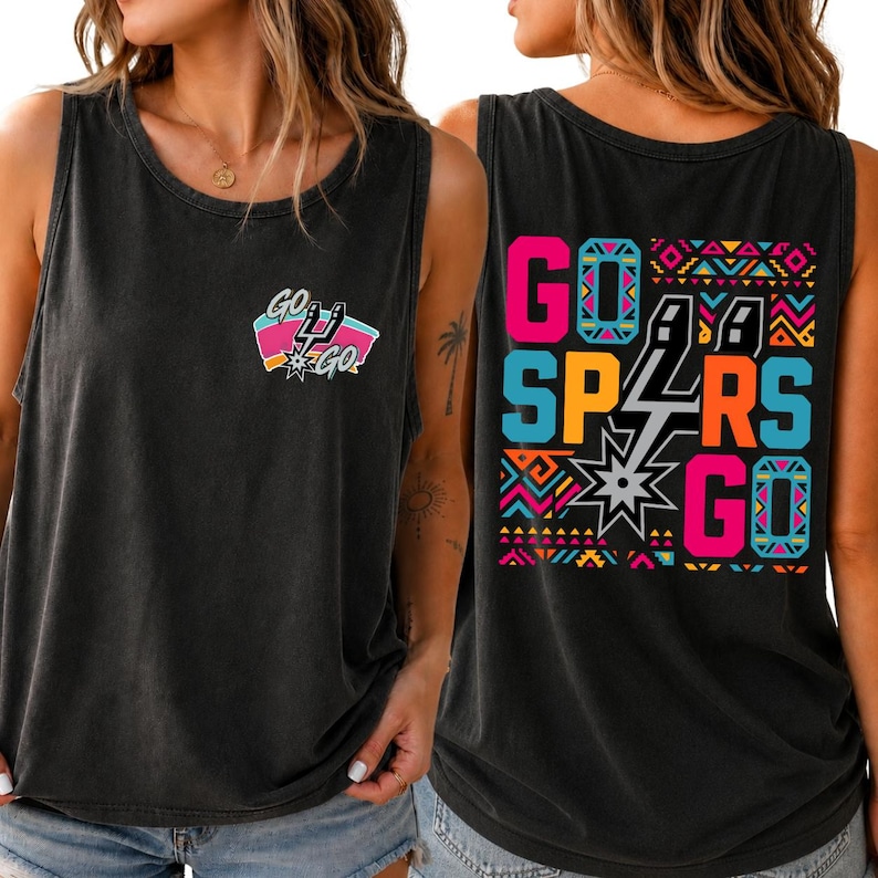Puede incluir: Una camiseta sin mangas negra con un peque&ntilde;o gr&aacute;fico en el pecho que incluye el texto "GO GO" y un logotipo de equipo. La parte trasera muestra un gr&aacute;fico grande y colorido con el texto "GO SPURS GO" rodeado de patrones geom&eacute;tricos ne&oacute;n.