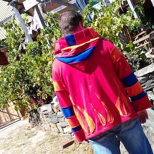 May include: A red hoodie with orange and blue stripes on the sleeves. The back of the hoodie features a large embroidered design of flames.