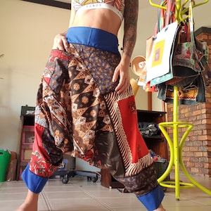 May include: A pair of colorful patchwork harem pants with a blue waistband. The pants are made of a variety of fabrics, including paisley, floral, and geometric patterns.