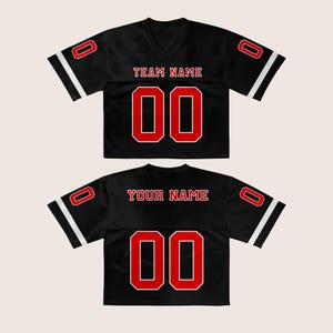 Puede incluir: Dos camisetas de f&uacute;tbol negras con detalles rojos y blancos. La camiseta delantera tiene "TEAM NAME" sobre el n&uacute;mero "00". La camiseta trasera tiene "YOUR NAME" sobre el n&uacute;mero "00". Cada camiseta tiene el n&uacute;mero "0" en las mangas.