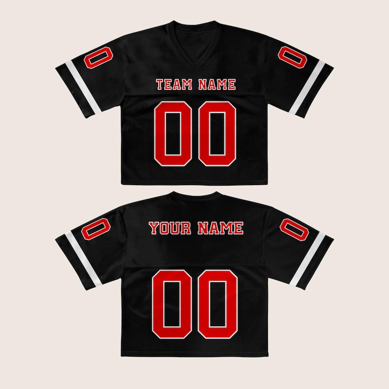 Puede incluir: Dos camisetas de f&uacute;tbol negras con detalles rojos y blancos. La camiseta delantera tiene "TEAM NAME" sobre el n&uacute;mero "00". La camiseta trasera tiene "YOUR NAME" sobre el n&uacute;mero "00". Cada camiseta tiene el n&uacute;mero "0" en las mangas.