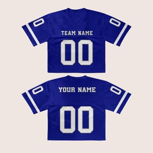 Puede incluir: Dos camisetas de f&uacute;tbol azul real. La camiseta delantera tiene el texto "TEAM NAME" encima del n&uacute;mero "00". La camiseta trasera tiene el texto "YOUR NAME" encima del n&uacute;mero "00". Ambas camisetas tienen detalles en blanco.