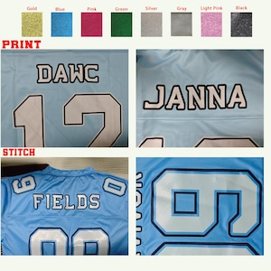 Puede incluir: Camiseta azul claro con letras y n&uacute;meros blancos. La camiseta presenta el nombre "DAWC" y el n&uacute;mero "12". Otra camiseta muestra el nombre "JANNA" y el n&uacute;mero "2". Una tercera camiseta muestra el nombre "FIELDS" y el n&uacute;mero "00".